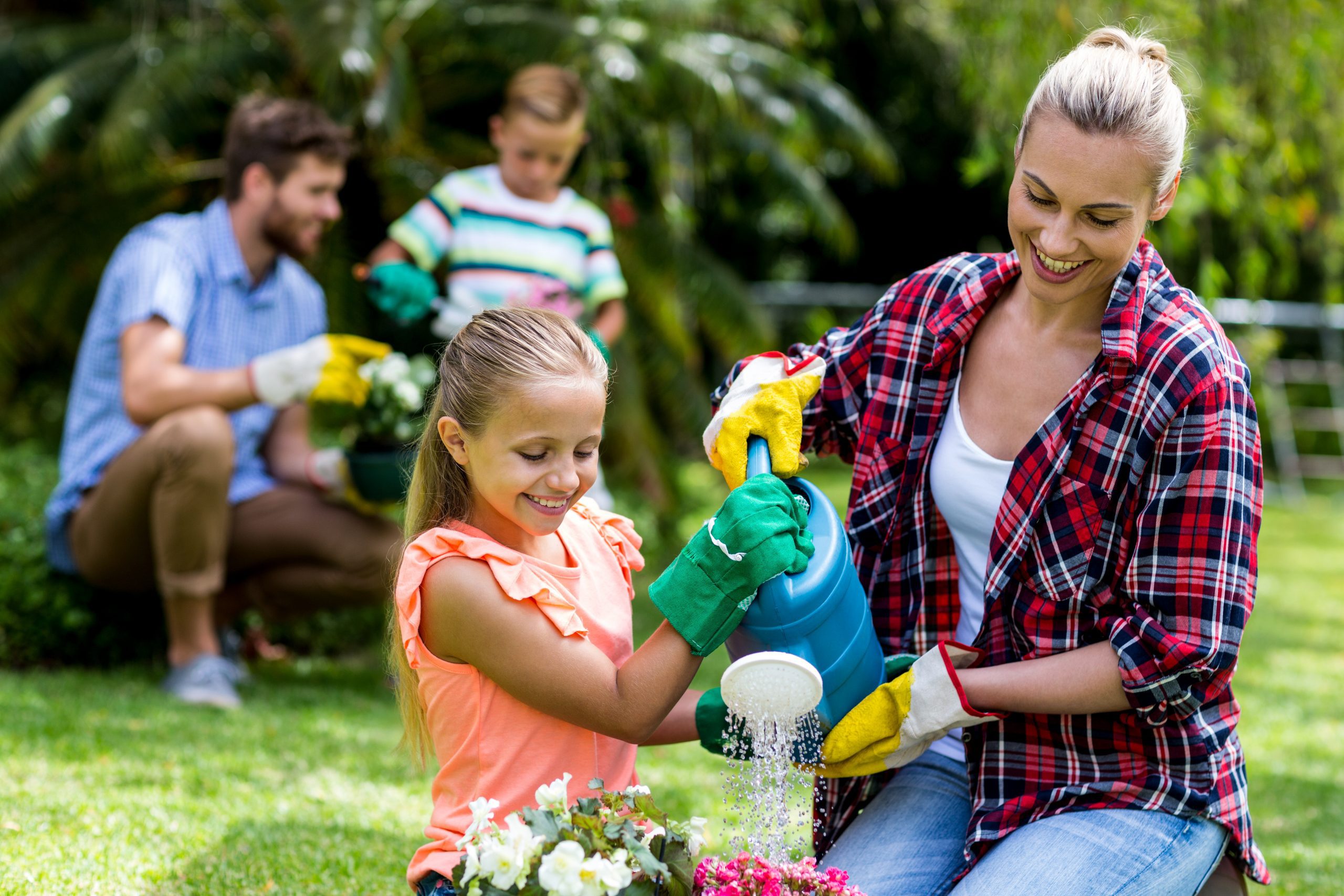 Mother and daughter watering flowers in yard. GLOVE DOVE® The Ultimate Glove Saver!™ can be used for your gardening gloves